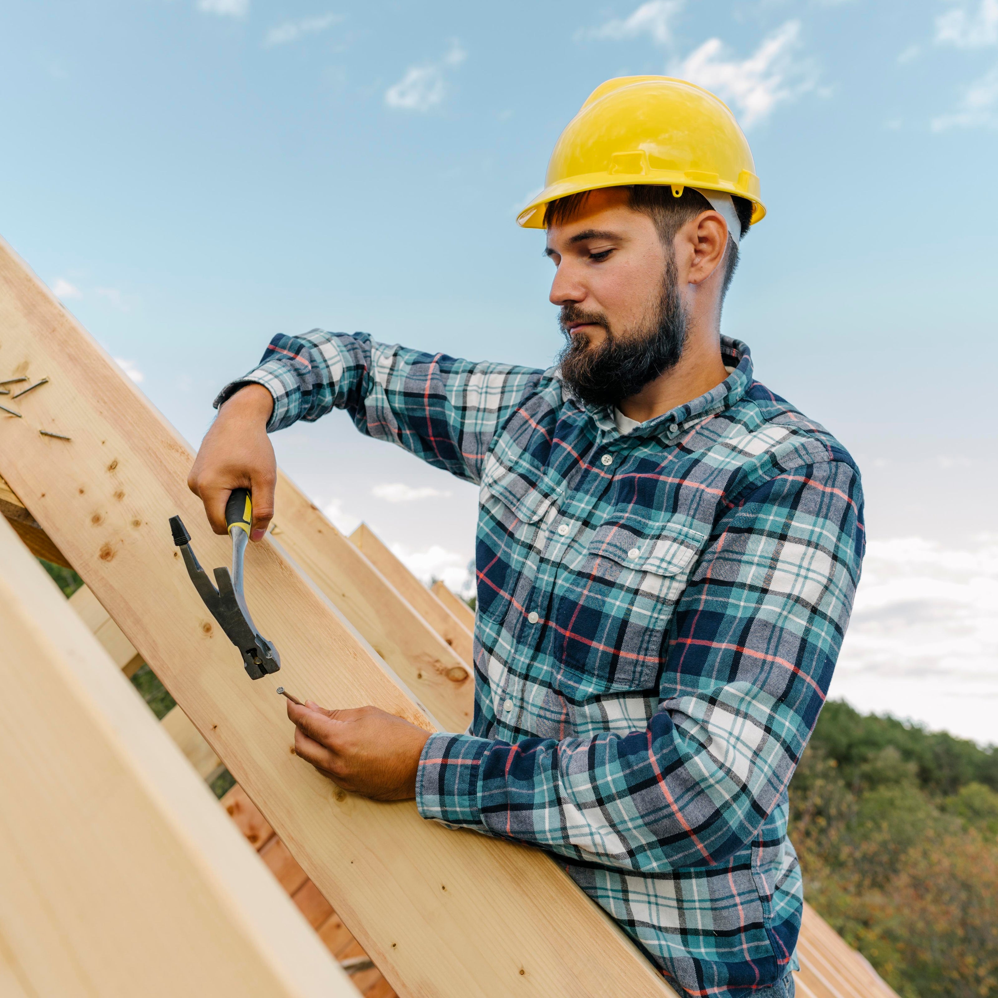 Man working on a roof with a yellow hard hat and tools.